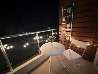 a table and two chairs on a balcony with lights at Studio B28 Sunny Island Chernomorez in Chernomorets