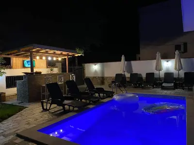 a pool with blue lighting in a backyard at night at Апартамент 