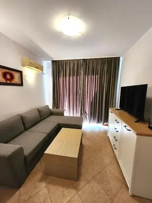 a living room with a couch and a flat screen tv at One bedroom guest suite in Sunny Beach