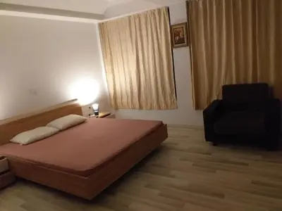 a bedroom with a bed and a black chair at къща за гости Градина in Aheloy