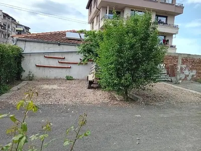 a house with a tree next to a building at къща за гости Градина in Aheloy