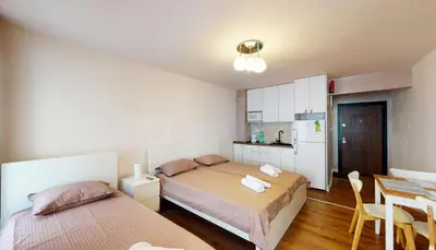a bedroom with two beds and a table and a kitchen at Markoni 4 in Burgas City
