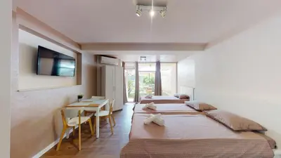 a room with three beds and a table and a tv at Markoni 5 in Burgas City