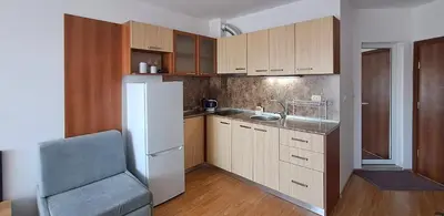 a kitchen with wooden cabinets and a white refrigerator at Александър Студио in Sveti Vlas