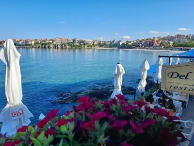 a view of a lake with white umbrellas and flowers at Къща за гости Кая in Sozopol