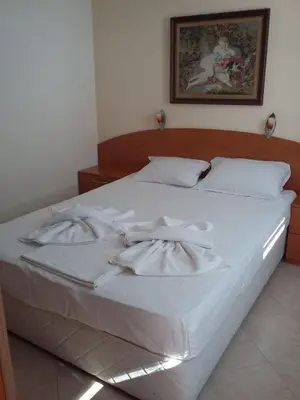 a white bed with white sheets and pillows on it at Къща за гости Кая in Sozopol
