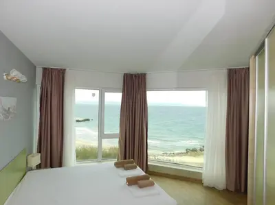 a bedroom with a large bed and a large window at Apartment Sunrise Pomorie in Pomorie