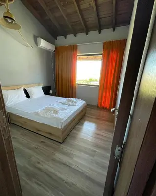 a bedroom with a bed and a window with orange curtains at Studio 8 Arapya in Tsarevo