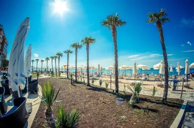 a beach with palm trees and chairs and umbrellas at Apartmán TTT in Burgas City