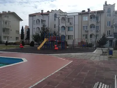 a playground in front of a large apartment building at Апартамент Браво in Sunny Beach