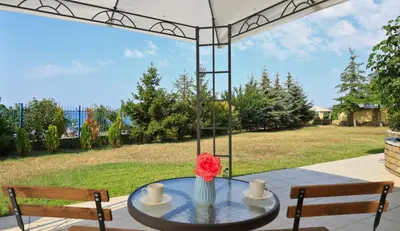 a table with a flower in a vase on a patio at Ravda Residence in Ravda