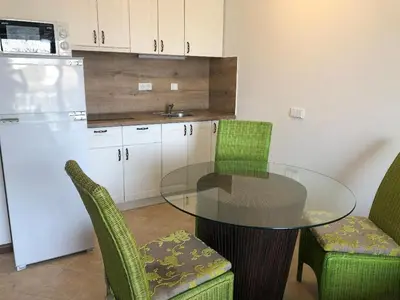 a kitchen with a glass table and chairs and a refrigerator at Oasis Resort & Spa Cozy Studio in Lozenets