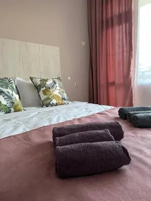 a bed with three towels on top of it at Guest house “Poli” in Nesebar