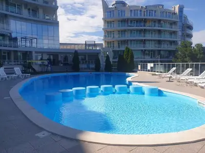 a large blue swimming pool with chairs and a building at Studio Silver Terace with Sea View for 4 person in Byala
