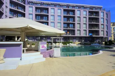 a hotel with a pool and an umbrella and a building at Апартамент в Рейнбоу 3 in Sunny Beach