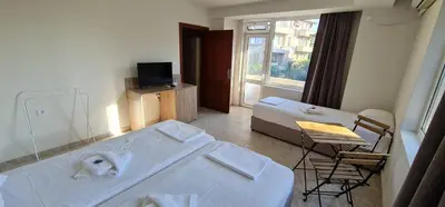 a room with a bed and a table and a window at Къща за гости Беглик Таш 2 in Primorsko