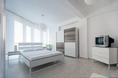 a white bedroom with a bed and a tv at Къща за гости Беглик Таш 2 in Primorsko