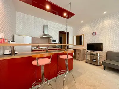 a kitchen with red cabinets and a counter with stools at Sunny Studio in Sunny Beach by Flat Mаnаger in Sunny Beach
