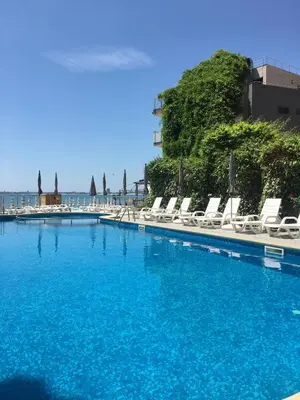 a swimming pool with lounge chairs and blue water at Апартаменти СЪНИ БЕЙ in Sunny Beach