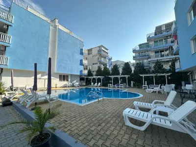 a pool with white lounge chairs next to a building at Blue Sky Apartments in Nesebar