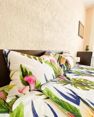 a bed with a colorful comforter and pillows at Blue Sky Apartments in Nesebar