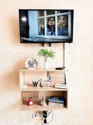 a television hanging on a wall with a shelf at Blue Sky Apartments in Nesebar