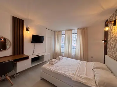 a white bedroom with a bed and a television at Sozopol Romance Apartments in Sozopol