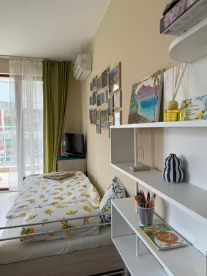 a bedroom with a bed and a desk and shelves at Апартамент Limoncini in Sozopol