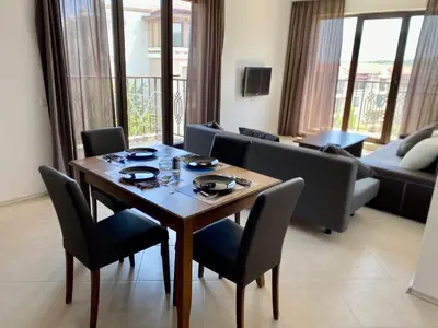 a dining table and chairs in a living room at Green Life Private apartments in Sozopol