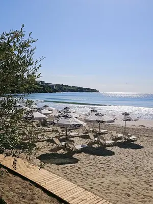 a beach with umbrellas and chairs and the ocean at Olive Villas Beach Hotel in Sozopol