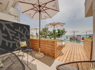 a patio with chairs and an umbrella and a pool at Olive Villas Beach Hotel in Sozopol