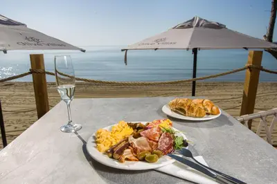 a table with two plates of food and a glass of wine at Olive Villas Beach Hotel in Sozopol