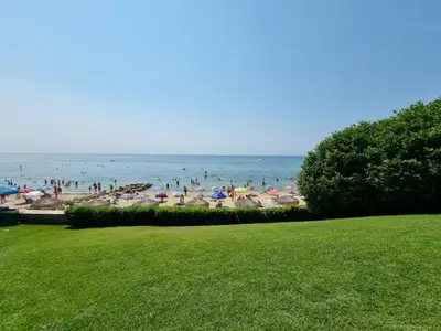 a group of people on a beach with umbrellas at Къща на брега на морето Свети Влас, Garden of Eden in Sveti Vlas