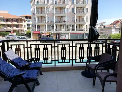 a balcony with chairs and an umbrella and a building at Lovely Studio in a Complex with a Pool by Flat Mаnаger in Sveti Vlas