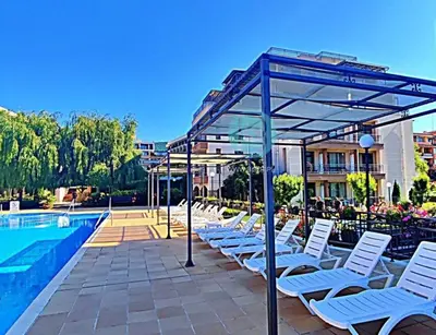 a row of white lounge chairs next to a swimming pool at Sorrento Sole Mare - Apartments by the beach in Sveti Vlas