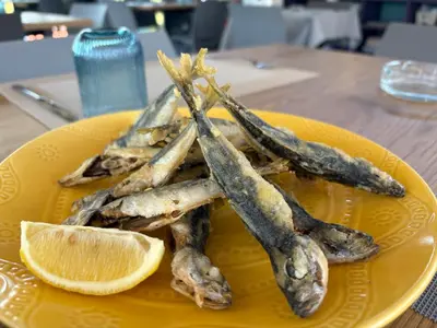 a yellow plate with some fish and a slice of an orange at Studio Maré Chernomorets in Chernomorets
