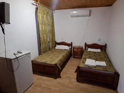 a room with two beds and a refrigerator at Къща за гости Катлея in Tsarevo