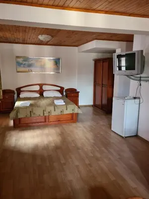 a bedroom with a bed and a flat screen tv at Къща за гости Катлея in Tsarevo