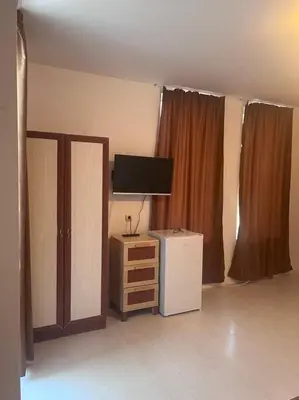 a living room with a tv and a dresser and a tvicterictericter at Къща за гости CANAVAN'S in Ravda