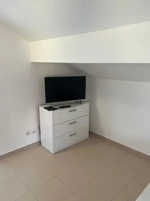 a living room with a tv and a white dresser at Къща за гости CANAVAN'S in Ravda