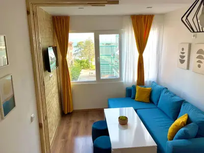 a living room with a blue couch and a window at Penthouse Panorama Sea View Apt. Pomorie in Pomorie