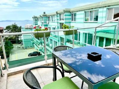 a balcony with a blue table and chairs and a building at Penthouse Panorama Sea View Apt. Pomorie in Pomorie