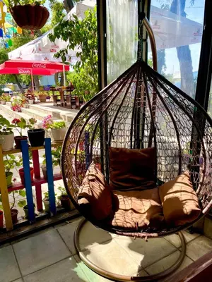 a hanging basket chair with pillows in a patio at Penthouse Panorama Sea View Apt. Pomorie in Pomorie