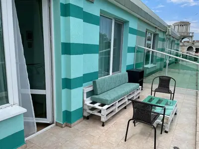 a balcony with a couch and a table and chairs at Penthouse Panorama Sea View Apt. Pomorie in Pomorie