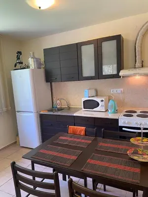 a kitchen with a table and a white refrigerator at 2-комнатные апартаменты у моря 10 бассейнов Crown Fort Noks in Sveti Vlas