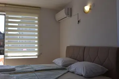 a bed with two pillows and a window with a blind at Guest House DARIS-APHRODEYA Къща за Гости ДАРИС-АФРОДЕЯ in Sozopol