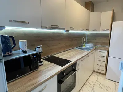 a kitchen with white cabinets and a sink and a microwave at Apartment The Room in Burgas City