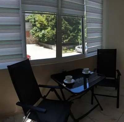 two chairs and a table in a room with two windows at Apartment The Room in Burgas City