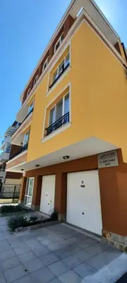 a yellow building with two garage doors in front of it at Нава 8 in Burgas City