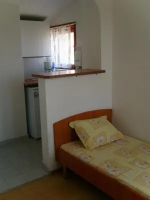 a small bedroom with a bed and a kitchen at Сотирови, самостоятелни стаи in Chernomorets
